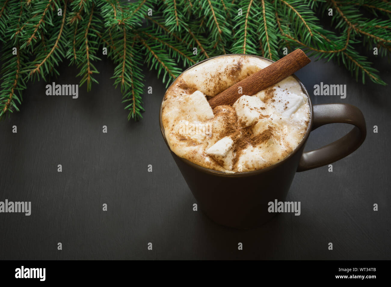 Natale tradizionale bevanda. Cioccolata calda con marshmallows e cannella su sfondo nero con albero di natale ramo. Holiday card. Close up. Foto Stock
