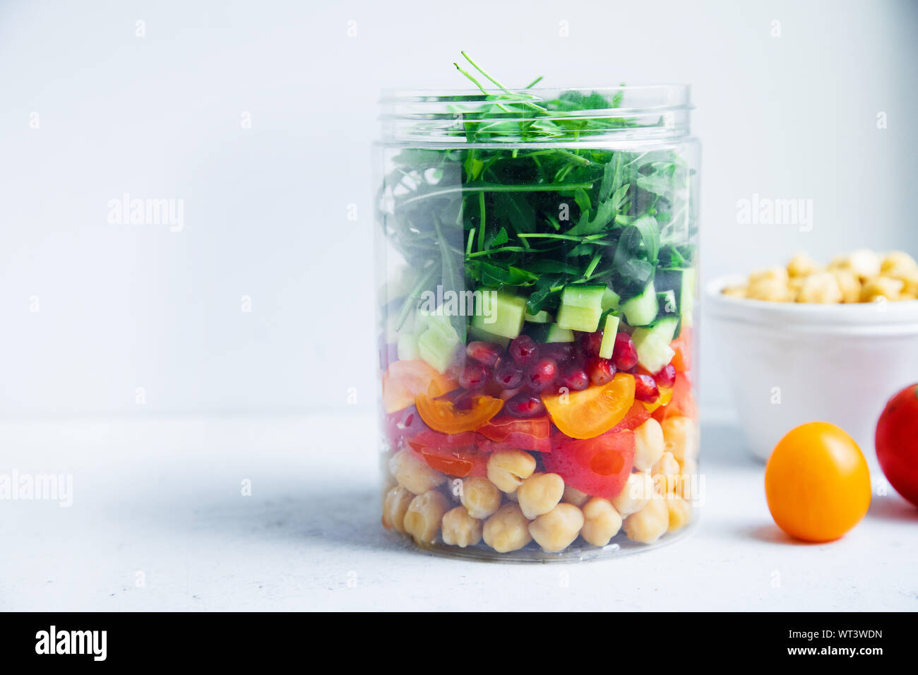 Una sana insalata con ceci e rucola in un vaso. Togliere facilmente il concetto di pranzo Foto Stock