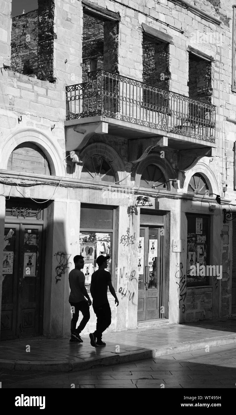 Figure che camminano oltre un edificio derelict in Syros, Grecia. Foto Stock