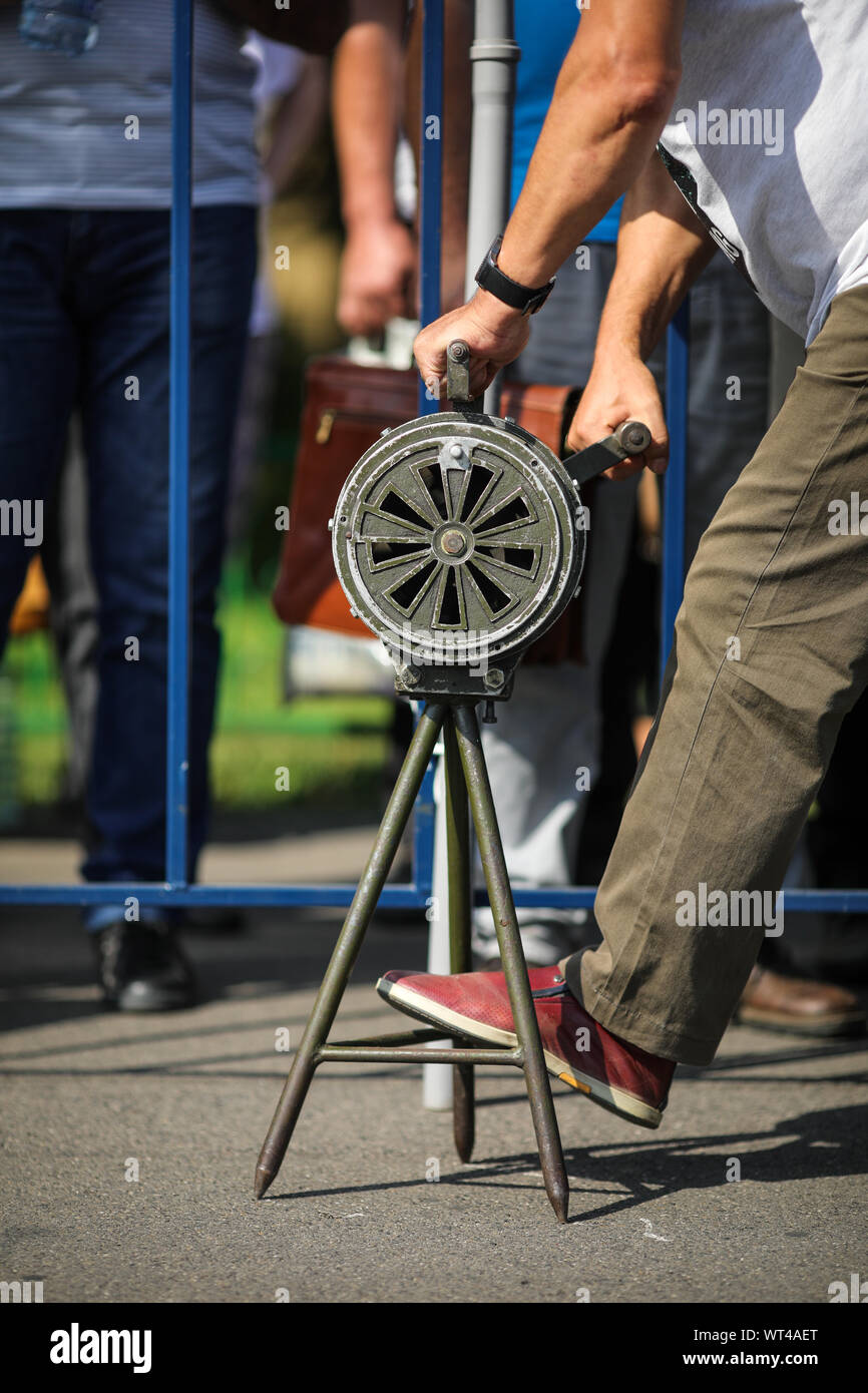 La profondità di campo di una immagine con un uomo la manipolazione di un annata manovella air raid siren Foto Stock