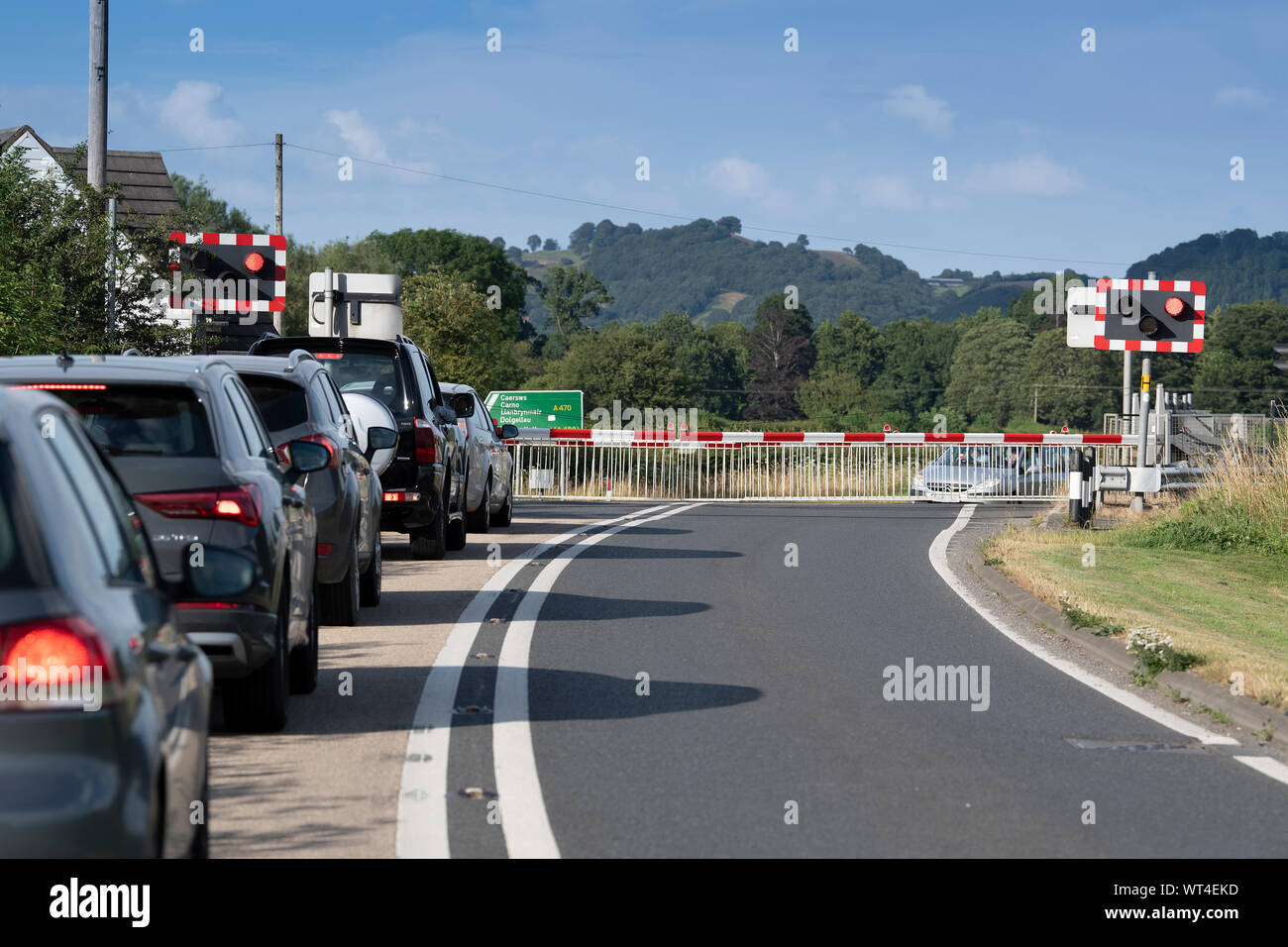 Accodamento di automobili fino ad un passaggio a livello come un treno che passa. Il Galles, UK. Foto Stock