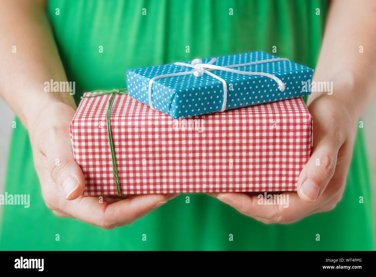 Donna in abito verde azienda piccoli doni fatti a mano in decorata carta craft in mani. Messa a fuoco selettiva. Natale e Anno Nuovo concetto. Foto Stock