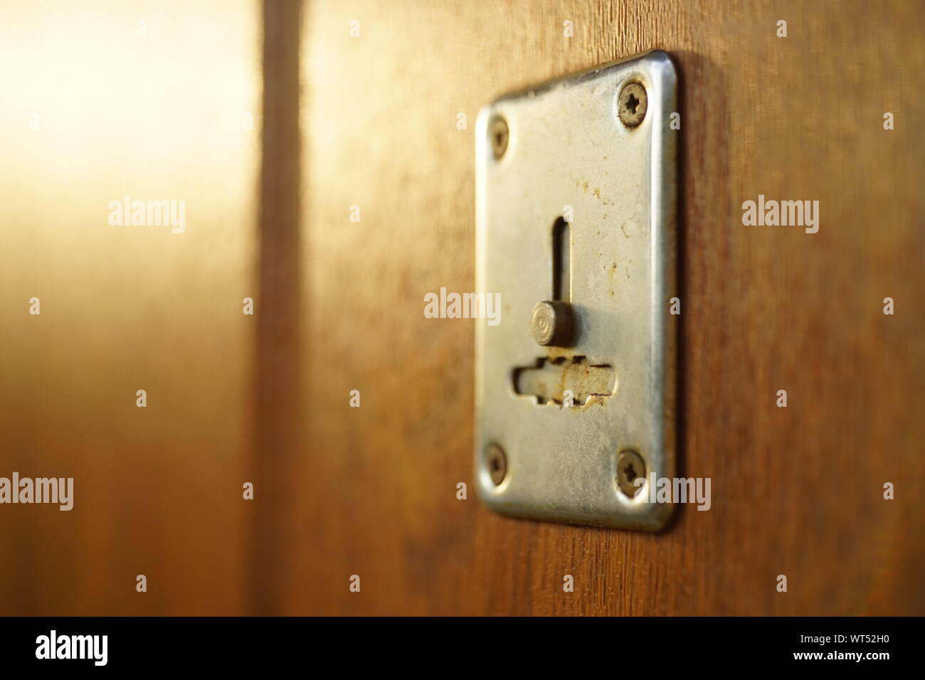 Brown porta in legno con chrome keyhole e raggi di sole Foto Stock