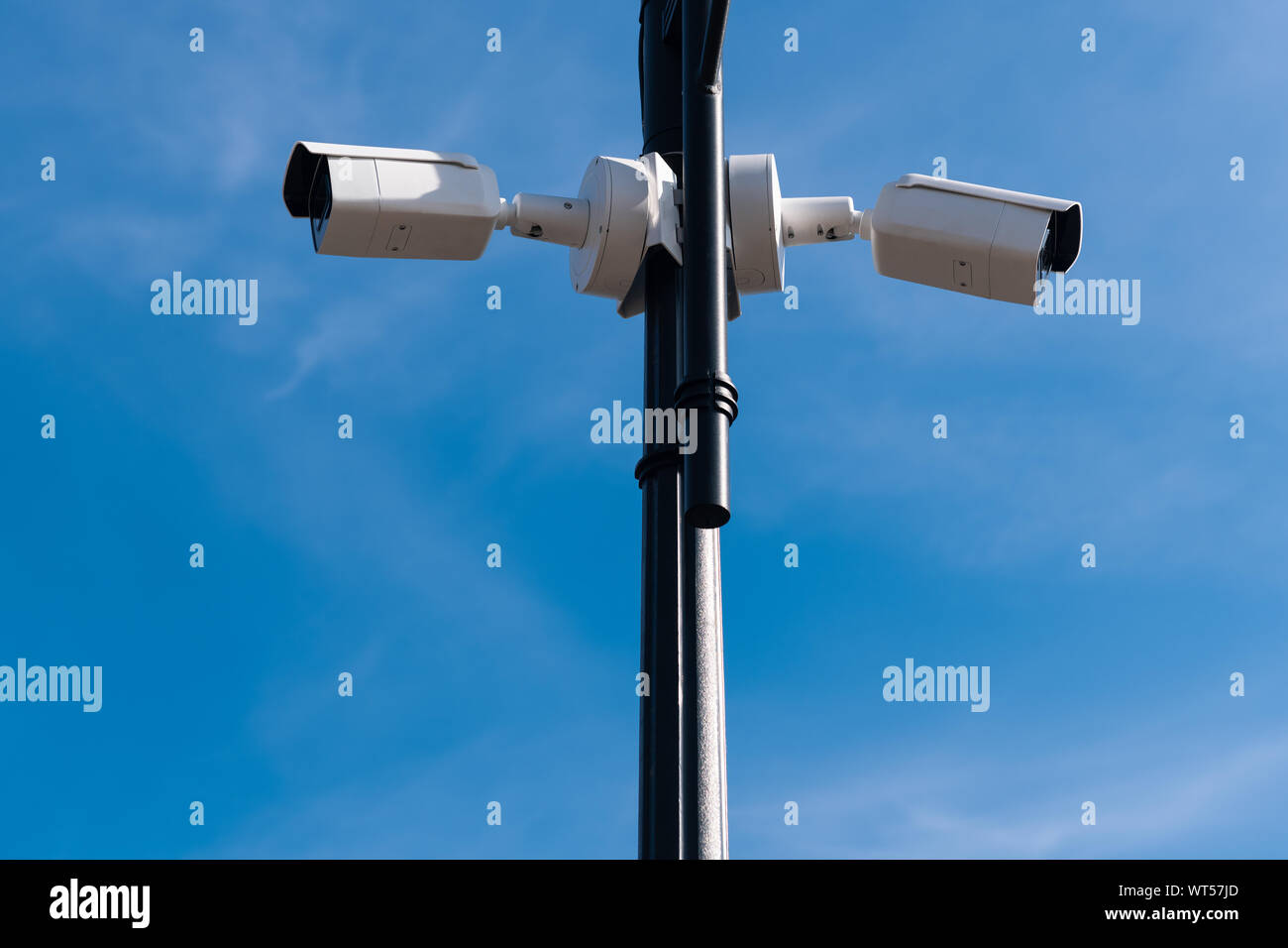 Due bianchi le videocamere di sorveglianza sul metallo lampada posta contro il cielo blu. La sicurezza di tutto il territorio. Il servizio di sicurezza è guardare. Copia dello spazio. Foto Stock
