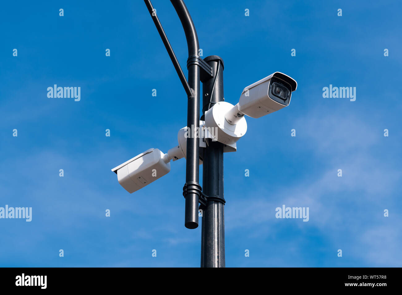 Due bianchi le videocamere di sorveglianza sul metallo lampada posta contro il cielo blu. La sicurezza di tutto il territorio. Il servizio di sicurezza è guardare. Copia dello spazio. Foto Stock