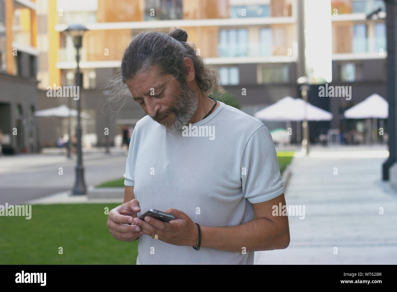 Uomo di mezza età in piedi sulla strada, controllando il suo smartphone Foto Stock