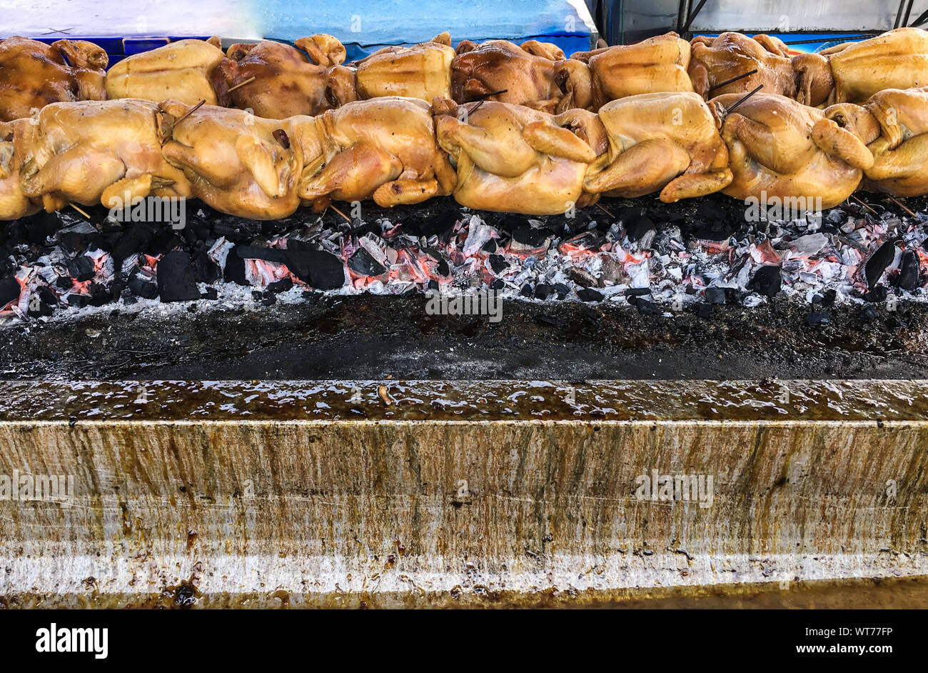 Pollo alla griglia fila sul metallo spiedino è la cottura sulla pila di carbone nel mercato tailandese Foto Stock
