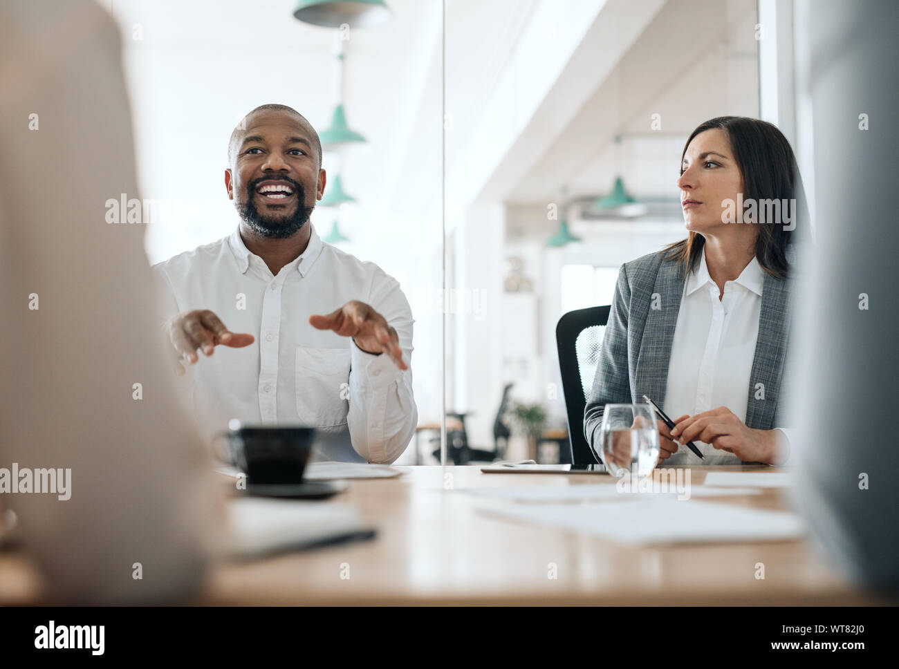 Sorridente africana imprenditore americano a parlare con i colleghi durante una riunione Foto Stock