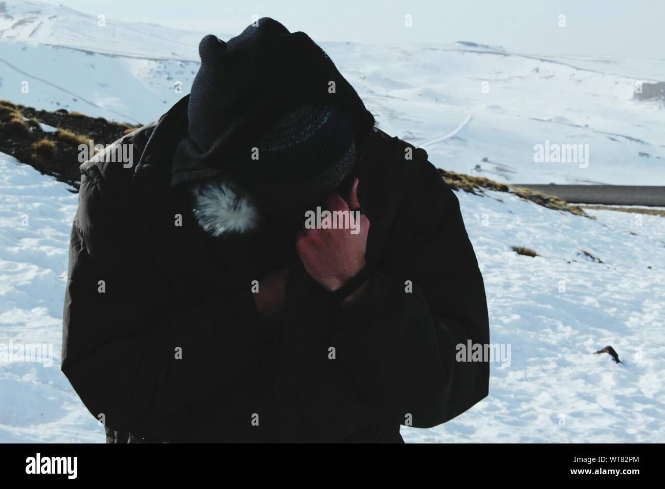 Uomo con la faccia oscurata permanente sulla coperta di neve montagna Foto Stock