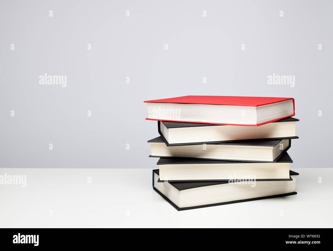 Pila di libri. Quattro libri rilegati neri e uno rosso su un tavolo Foto Stock