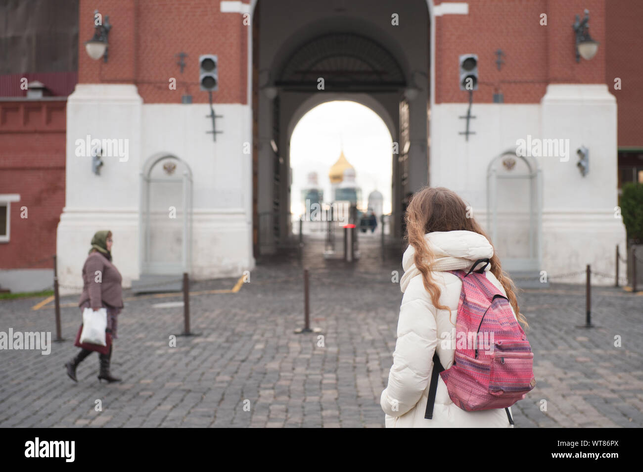Turista giovane ragazza con zaino guardando il Cremlino gates permanente sulla Piazza Rossa con la vecchia donna in velo le passeggiate su pavimentazioni Foto Stock
