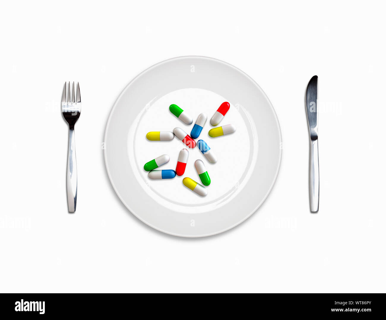 Pills e posata, piatto bianco, coltello e forchetta con un pasto di capsule di pillole, dipendenza da farmaci Foto Stock