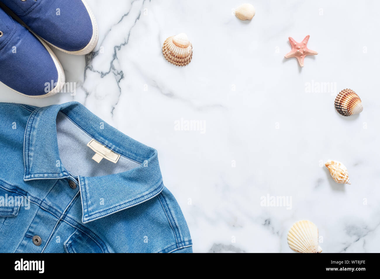 Telaio di confine di blu sneakers, jeans denim camicia, conchiglie su sfondo marmo. Elegante appartamento composizione laici, abbigliamento casual di bellezza blog di moda Foto Stock