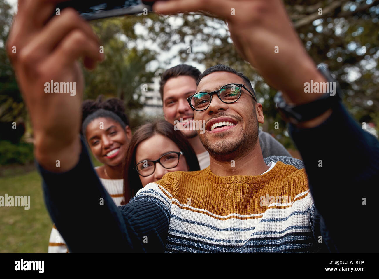 Sorridente brasiliano americano uomo prendendo selfie sul telefono cellulare godendo del tempo insieme con i suoi amici Foto Stock