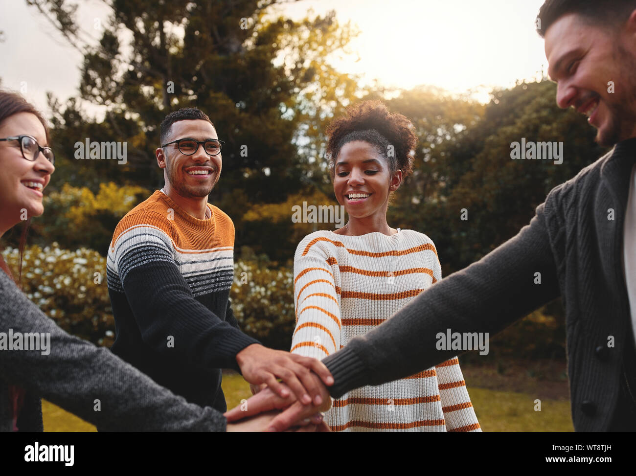 Gruppo di sorridente amici diverse mani di impilamento per esprimere unità e supporto insieme nel parco sorridenti - il lavoro di squadra Foto Stock