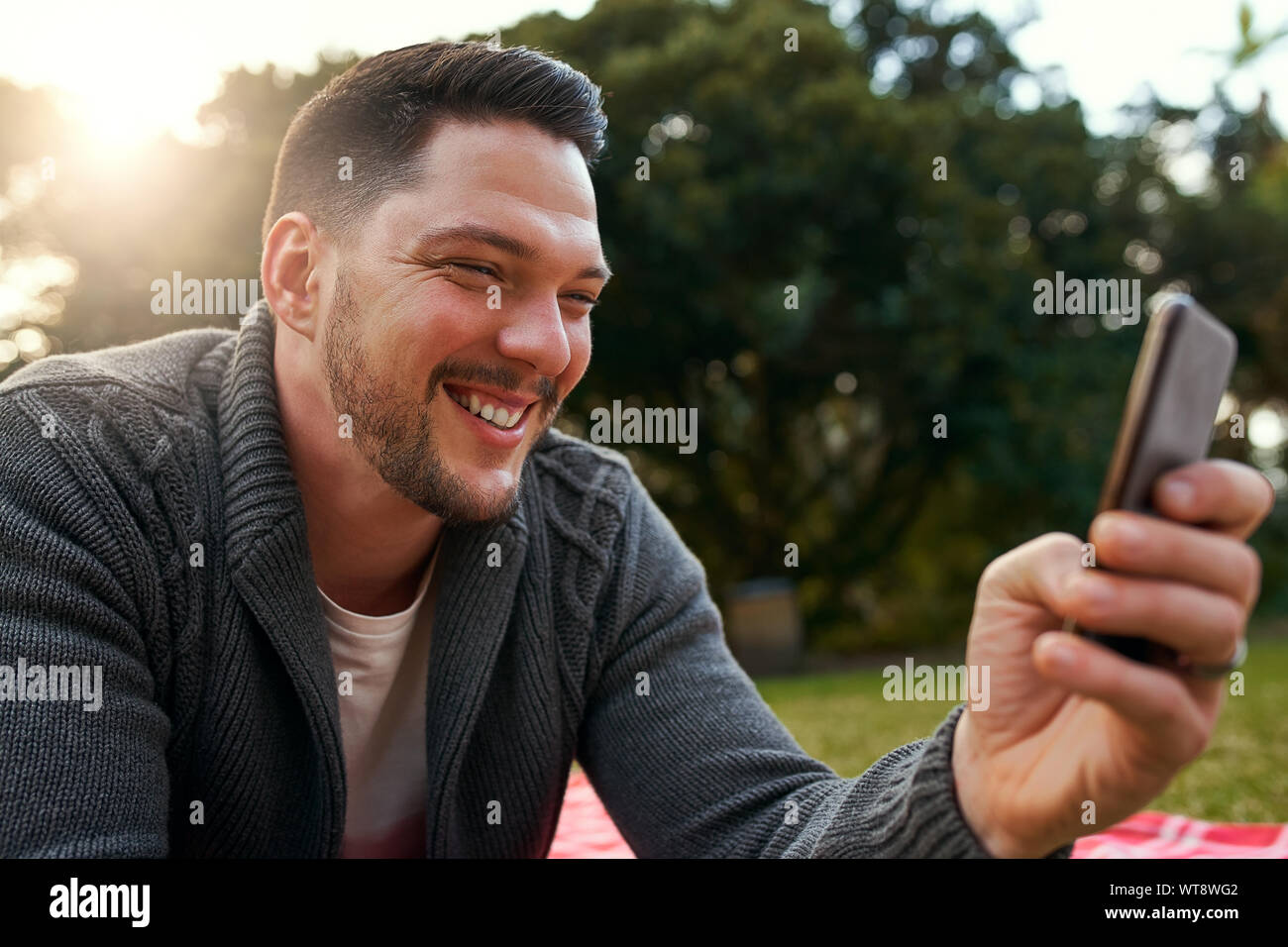 Uomo bello godendo nel parco tenendo selfie sul telefono cellulare Foto Stock