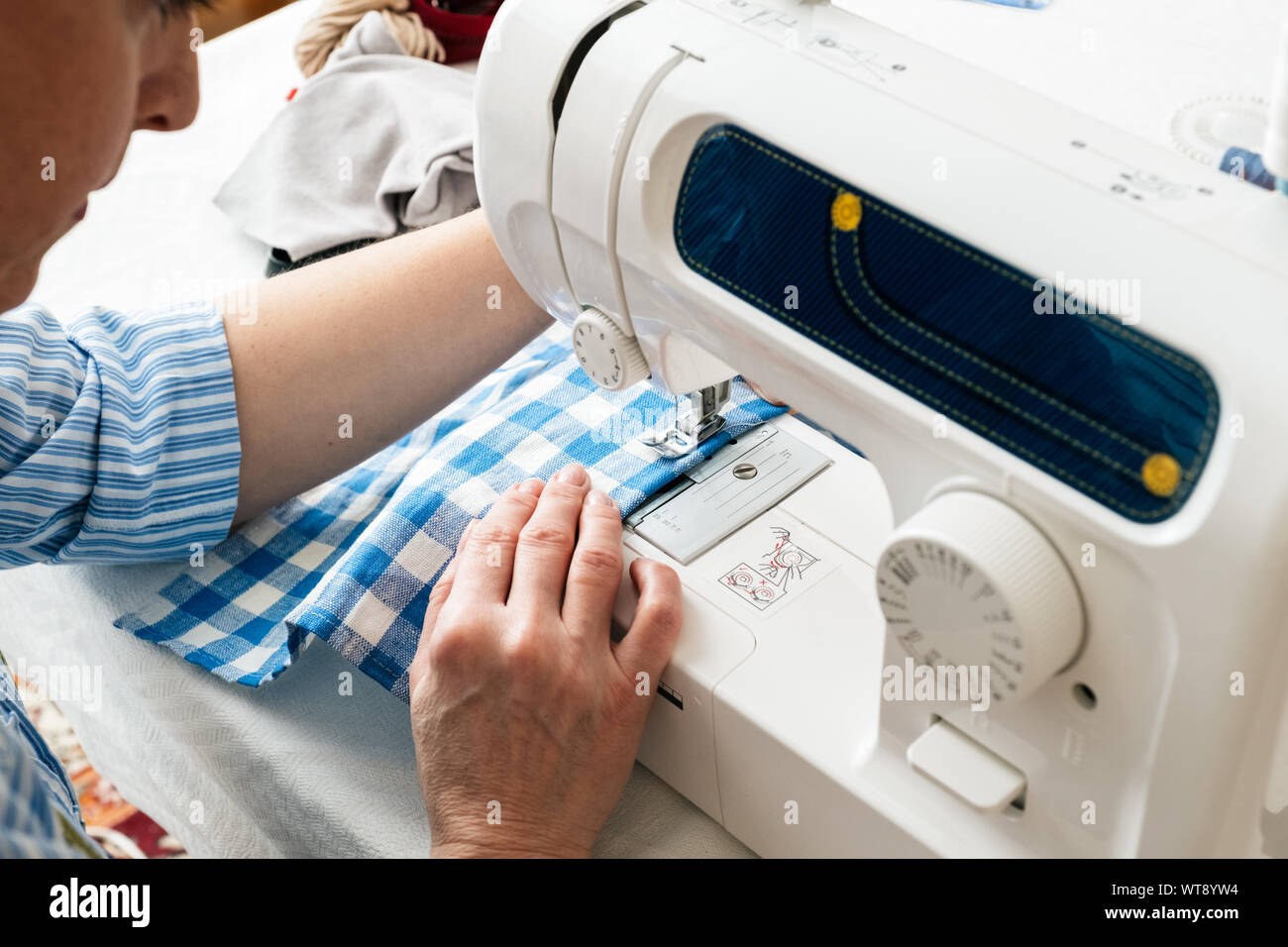 Le mani di una donna con una macchina da cucire in officina su misura. Foto Stock