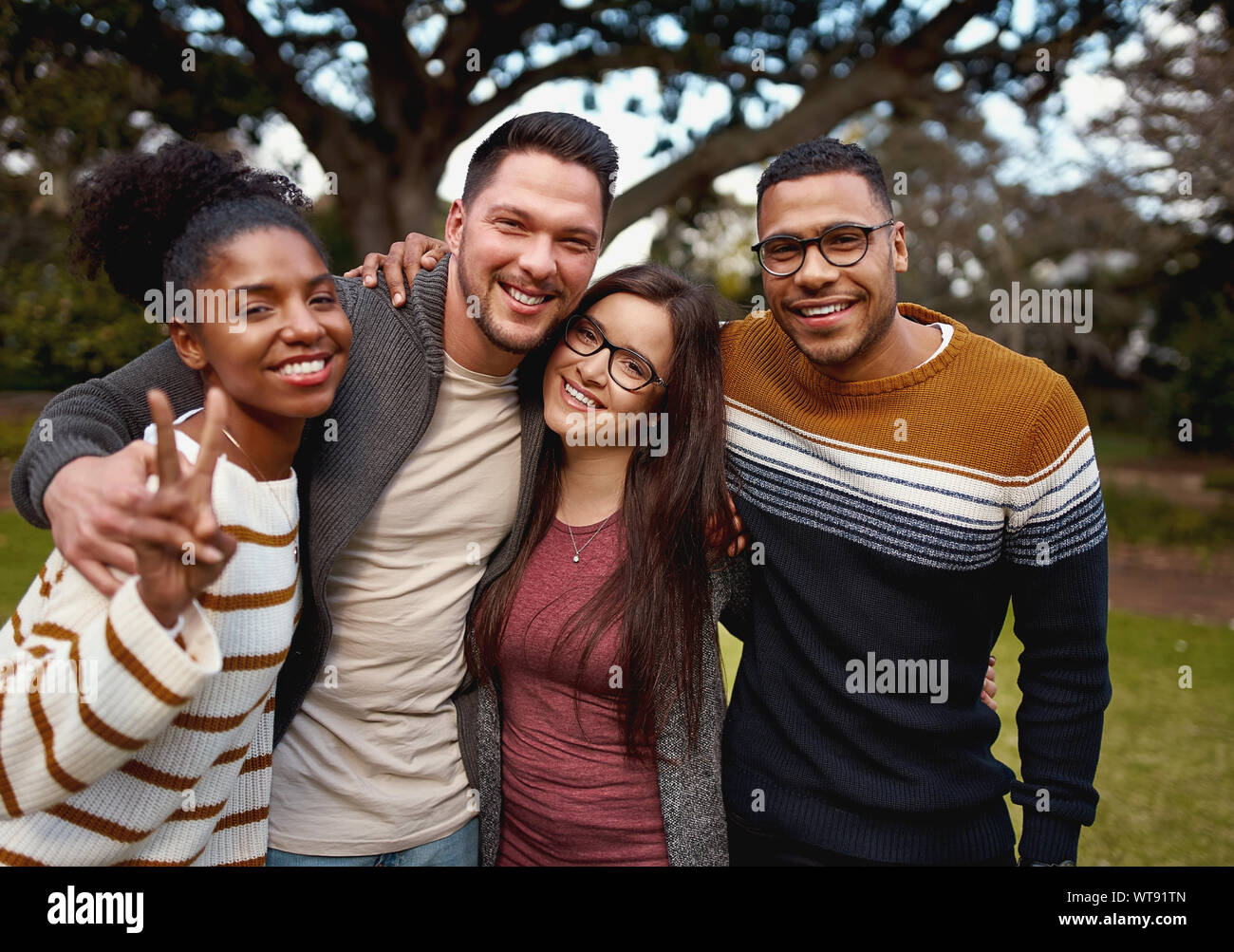 Gruppo di giovani multi razziale americano africano amici in piedi e sorridente insieme nel parco - Vestiti caldi Foto Stock