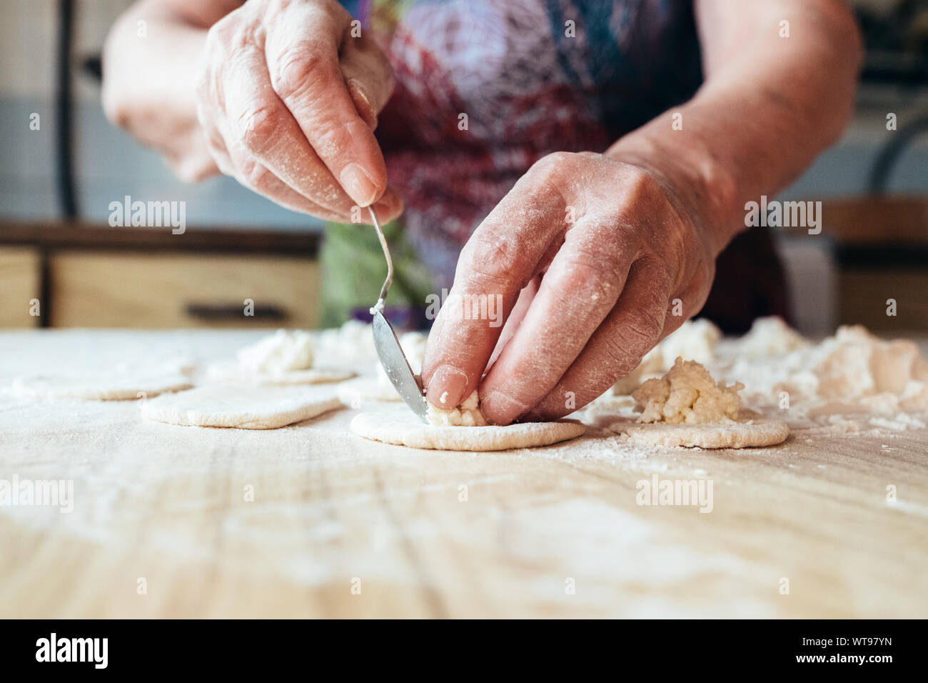 Stropicciata nonne mani mettendo il riempimento in pasta. Vista ravvicinata. Foto Stock
