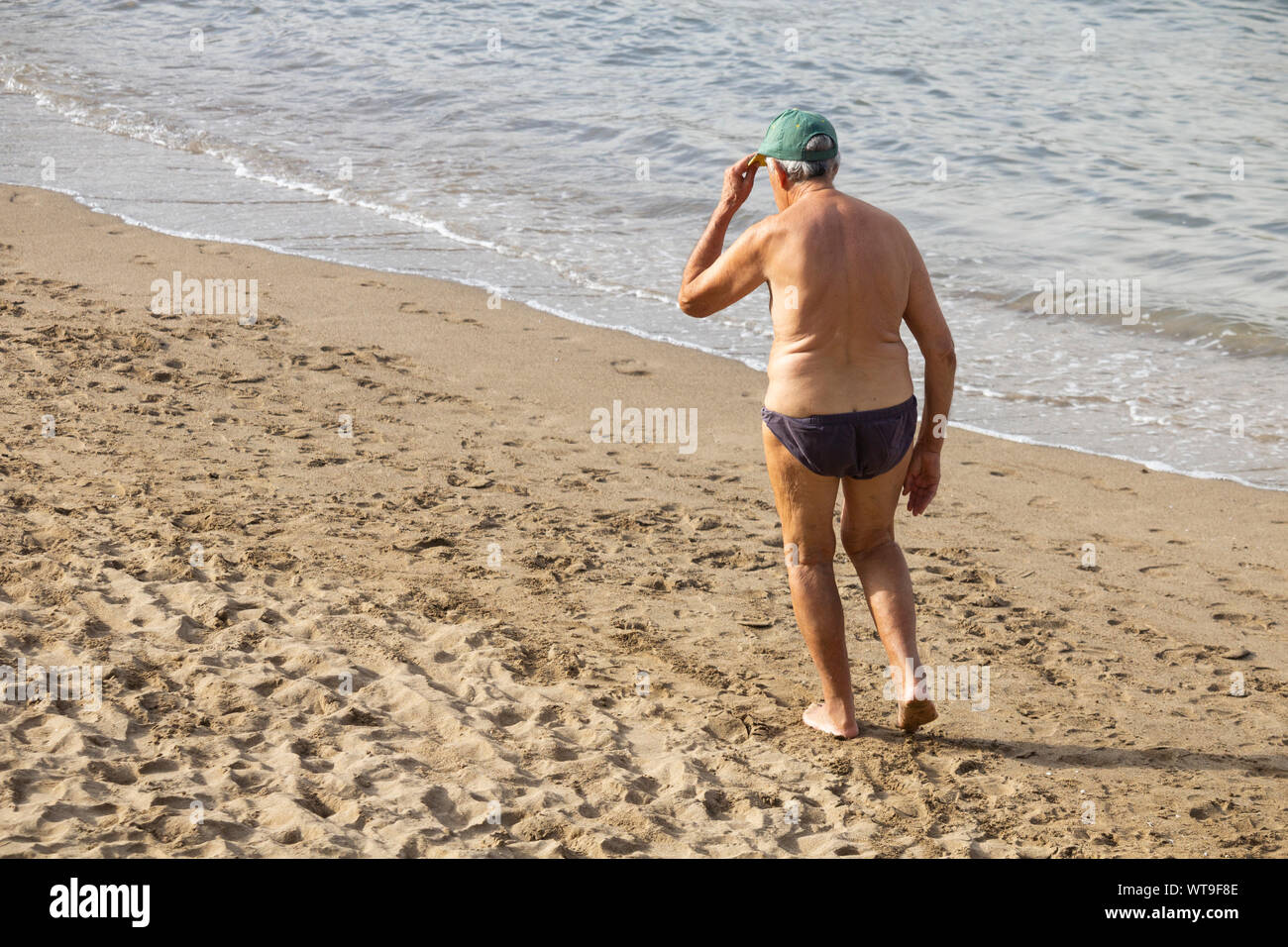 Vista posteriore del vecchio uomo a camminare sulla spiaggia. Foto Stock