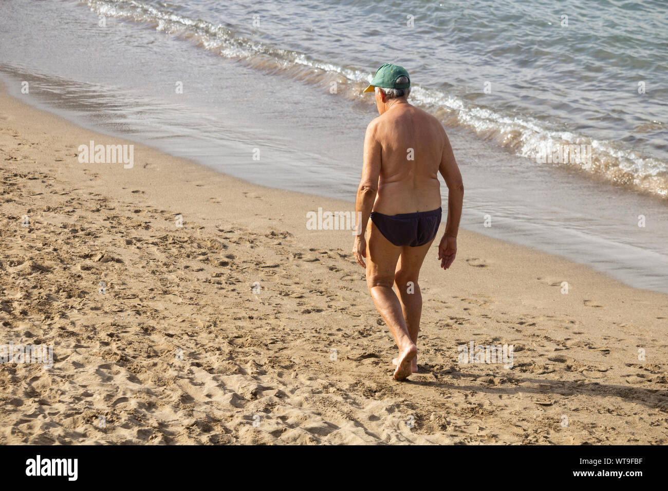 Vista posteriore del vecchio uomo a camminare sulla spiaggia. Foto Stock