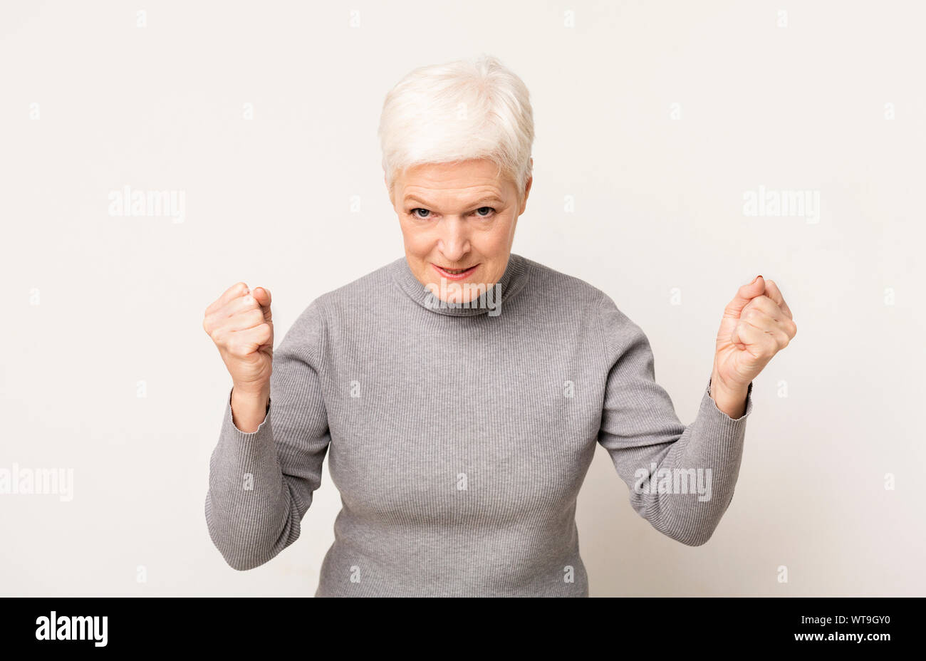 Arrabbiato donna anziana che minacciano di qualcuno con alzata a suon di pugni Foto Stock