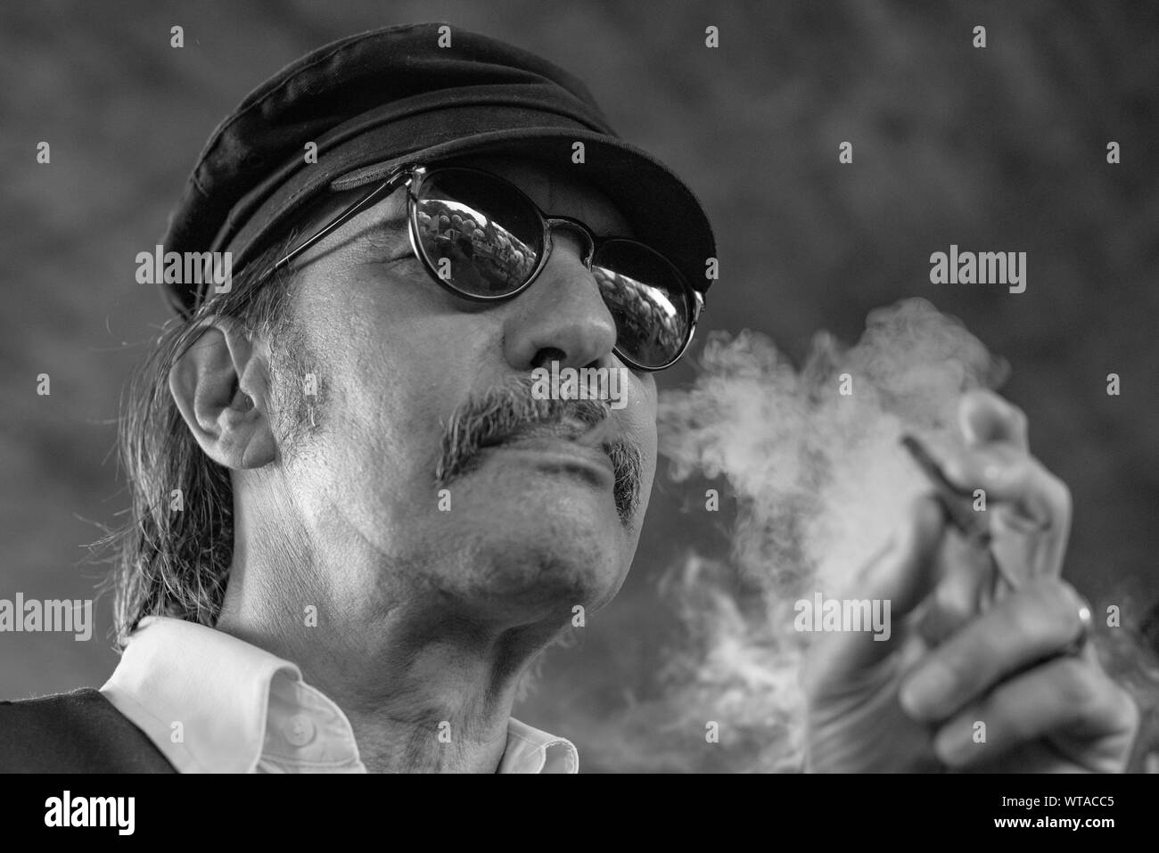 Uomo comunista indossando occhiali da sole e berretto, fuma durante una manifestazione di protesta Foto Stock