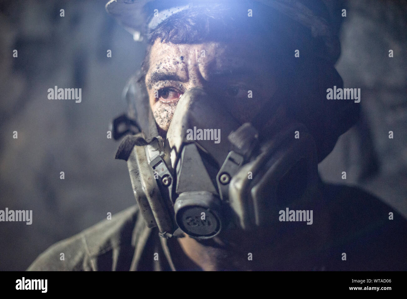 Il minatore al lavoro utilizzando hardhat e una maschera antipolvere Foto Stock