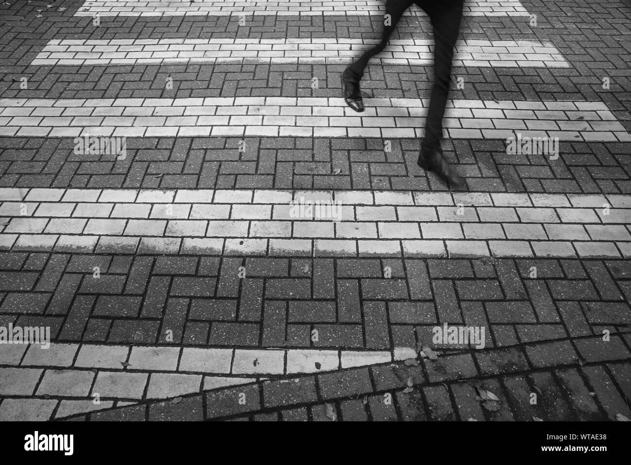 Uomo che attraversa un crosswalk Foto Stock