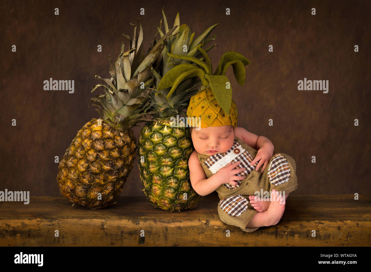 Carino immagine composita con ananassi freschi e un neonato in feltro ananas hat Foto Stock
