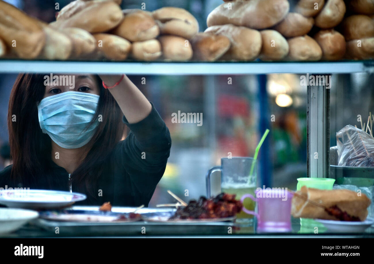 La donna lavora nelle strade food business indossando anti-inquinamento mask Foto Stock