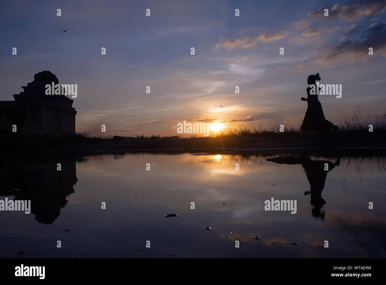 Donna in silhouette in esecuzione nel punto del tramonto di Hampi Foto Stock