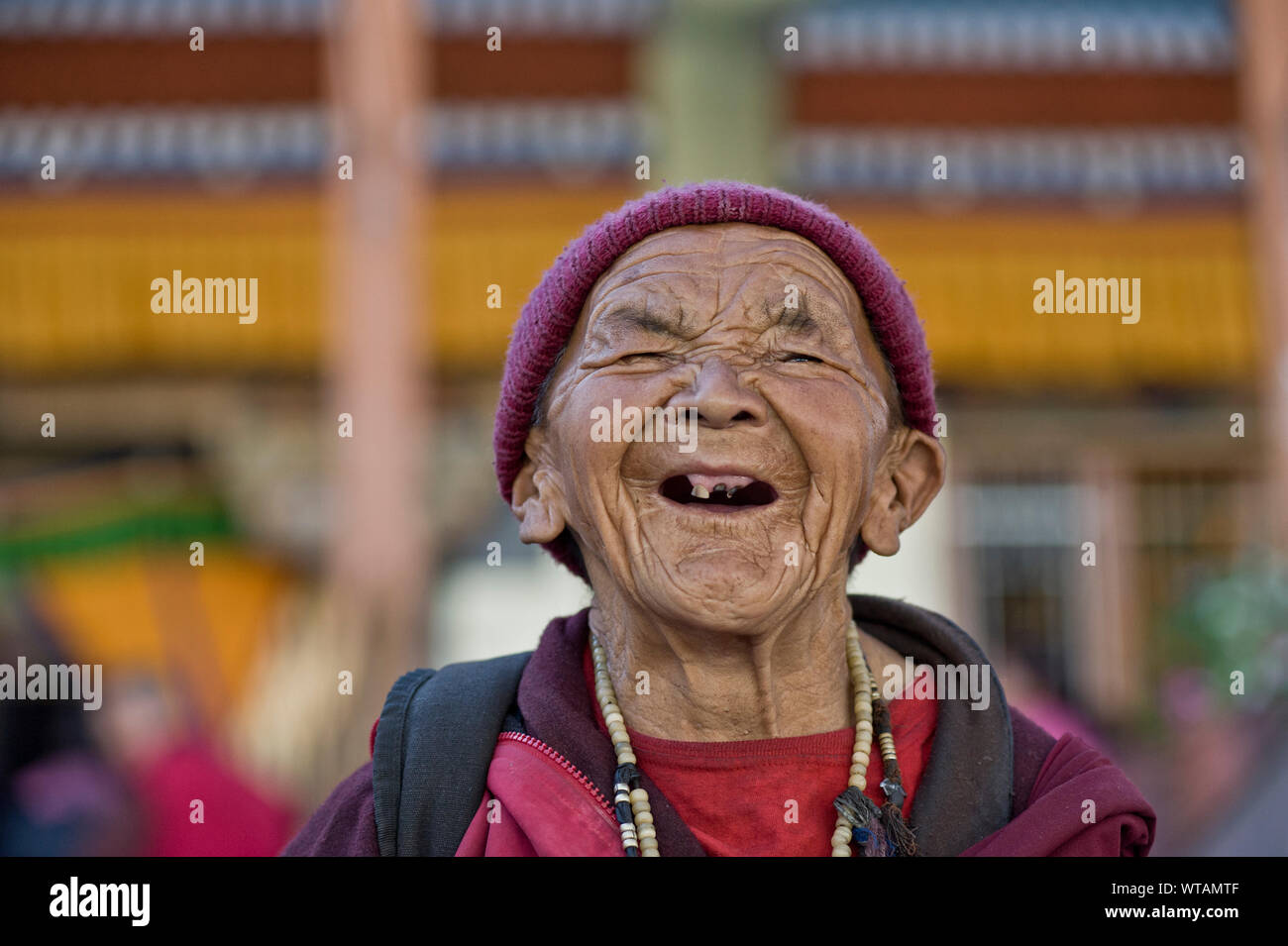 Vecchia Signora priva di denti ridere in una celebrazione buddista Foto Stock