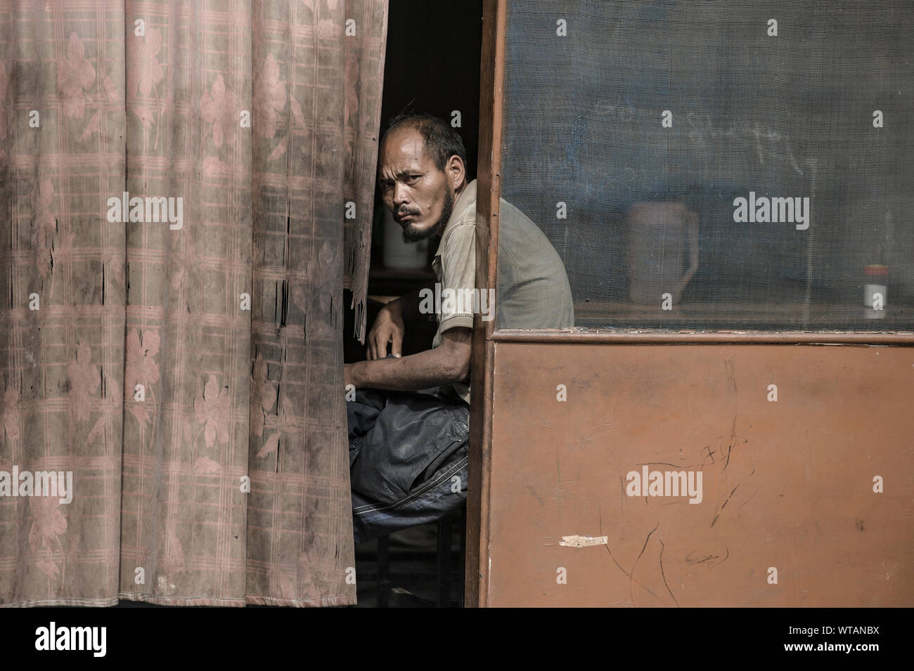 Mechanic nel tempo di pausa si guarda attraverso una vecchia tenda Foto Stock