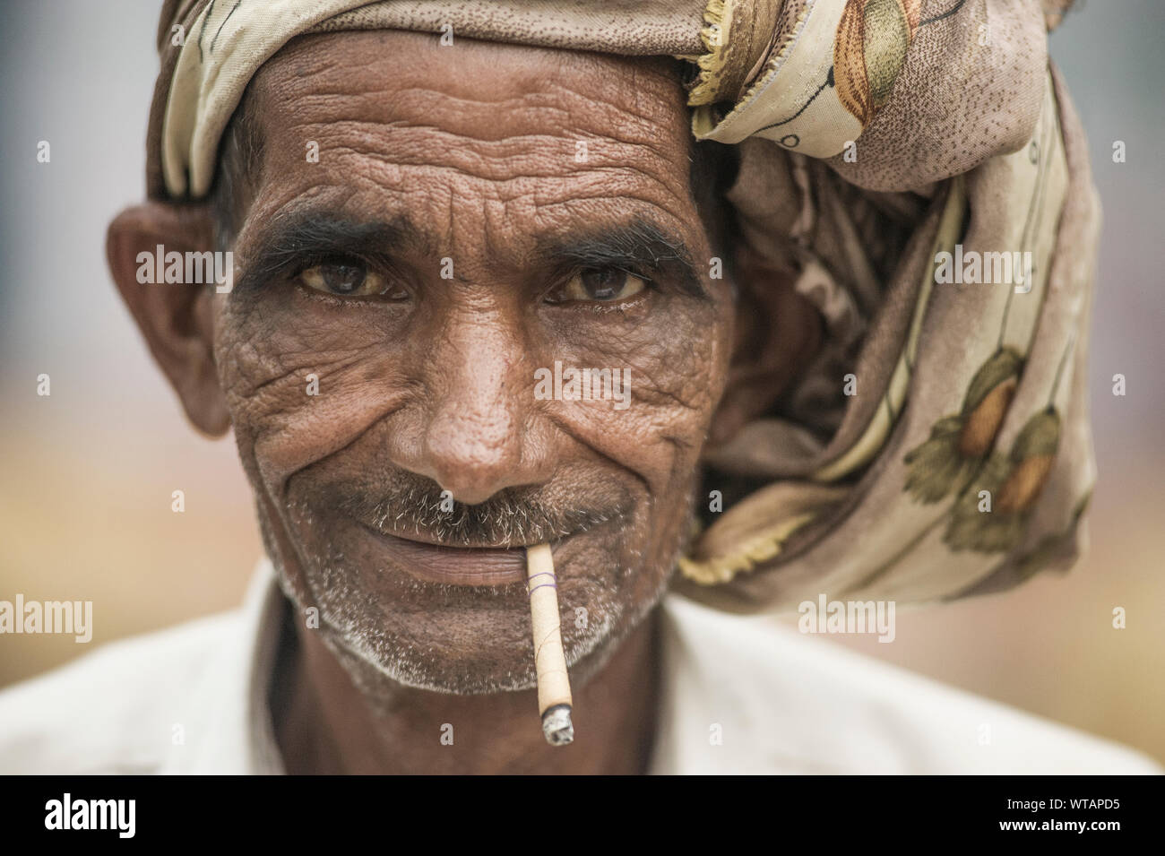 Il vecchio uomo indù fumatori di sigarette di paglia Foto Stock
