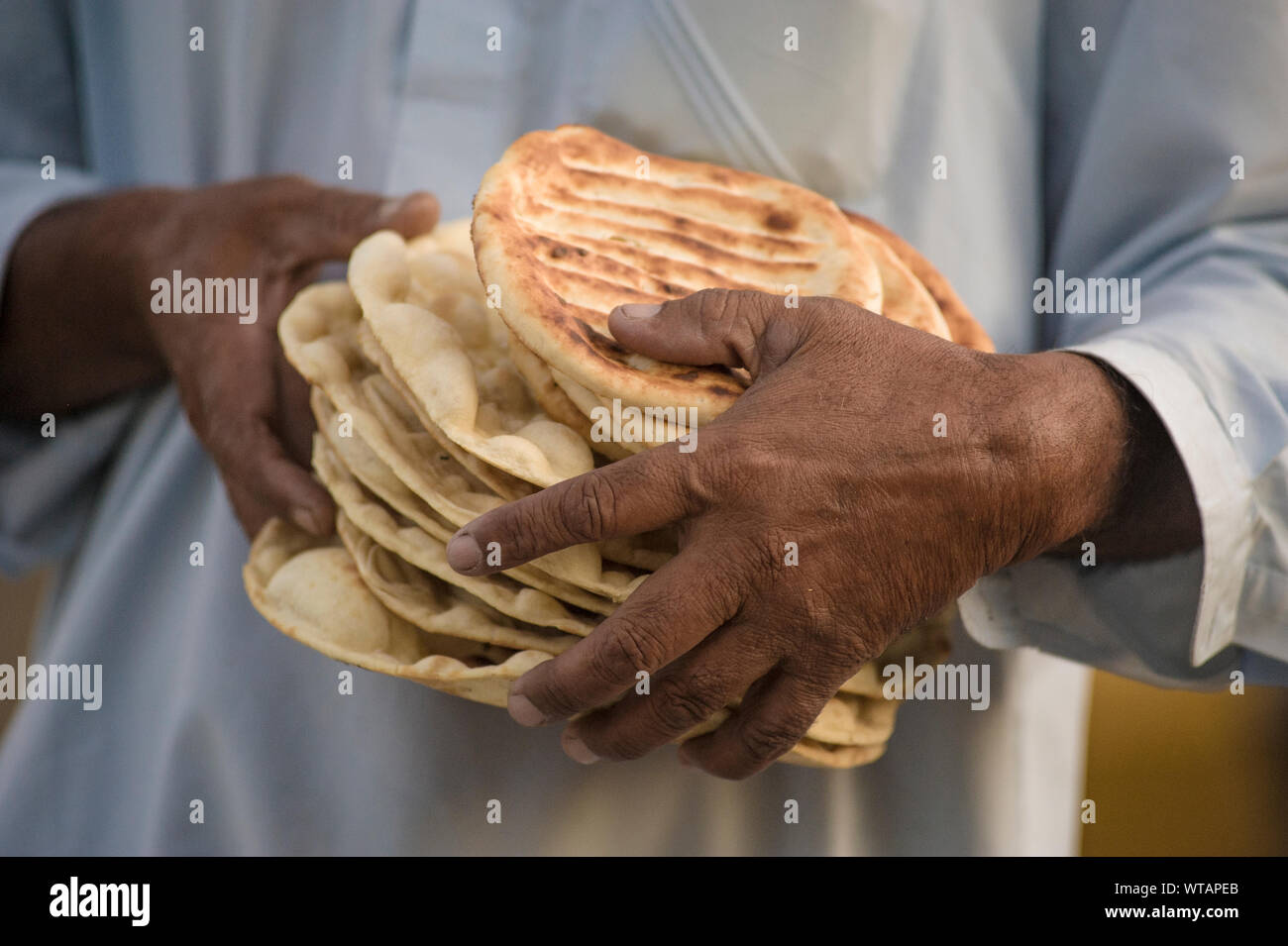 Uomo che porta un mazzetto di czhot o girda, tradizionale pane del Kashmir Foto Stock