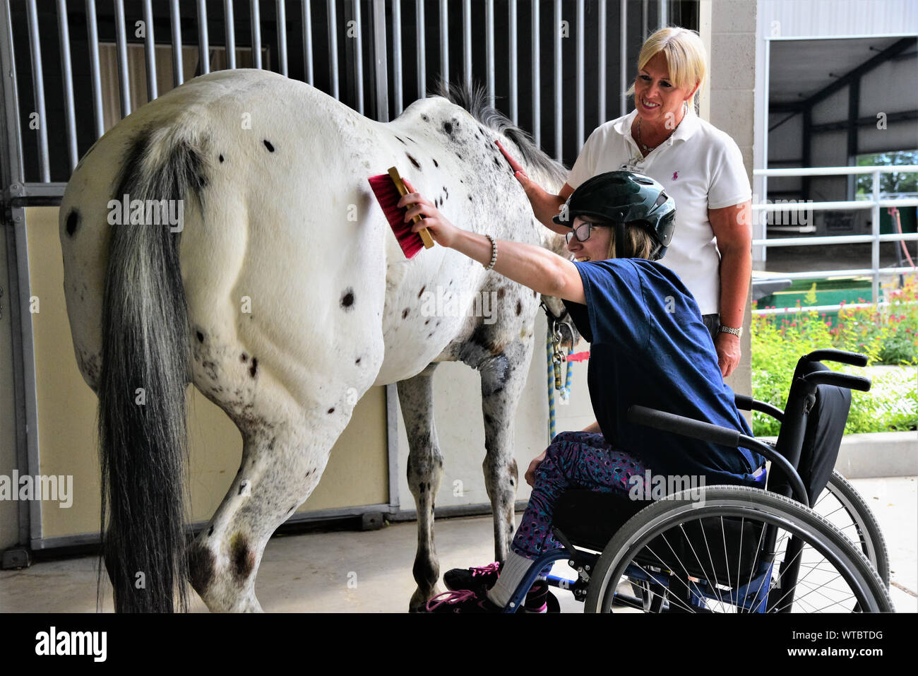 Equina terapia assistita per sfidato i bambini e gli adulti. Volontari assistono con aiutare i pazienti ottenere coraggio e speranza con i cavalli come un puntello. Foto Stock