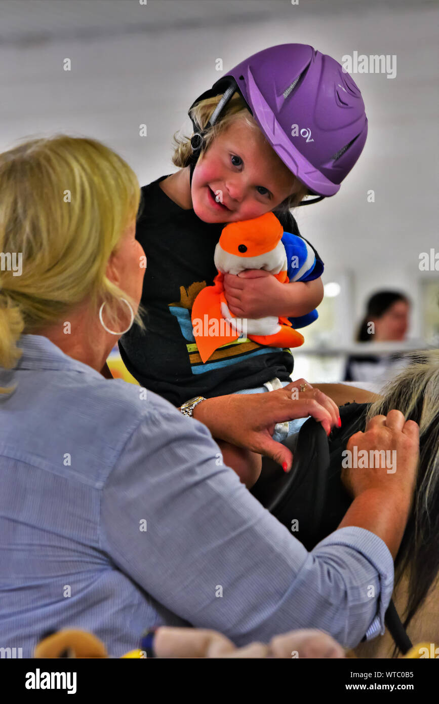 Equina terapia assistita per sfidato i bambini e gli adulti. Volontari assistono con aiutare i pazienti ottenere coraggio e speranza con i cavalli come un puntello. Foto Stock