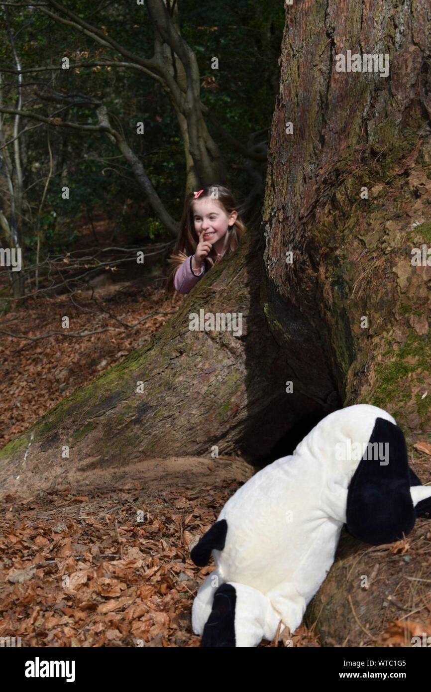 Persona in Costume di giocare a nascondino con la ragazza alla struttura ad albero nella foresta Foto Stock