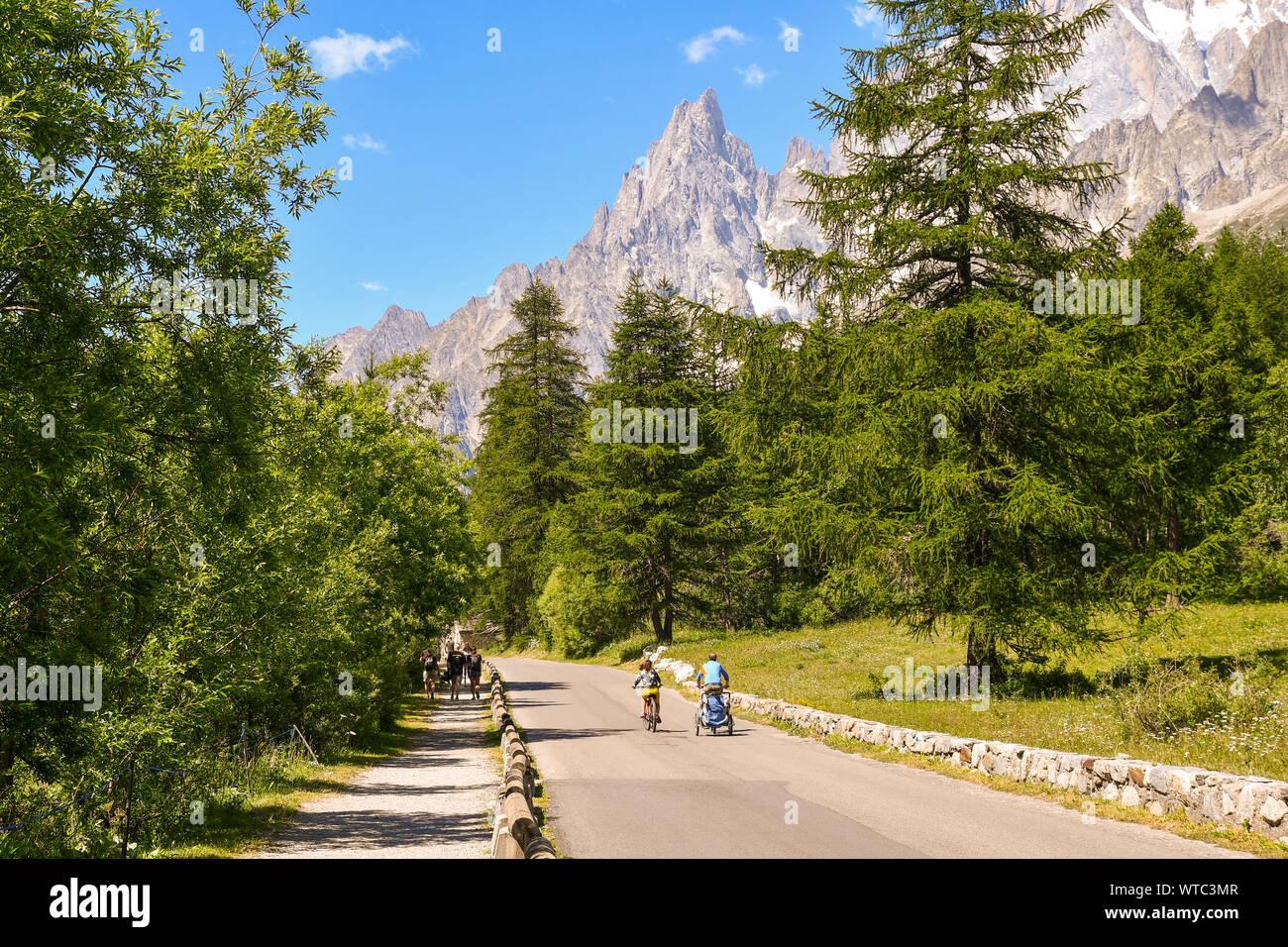 Vista della Val Ferret, una valle alpina ai piedi della catena montuosa del Monte Bianco con la Aiguille Noire di picco e di turisti, Courmayeur, Italia Foto Stock