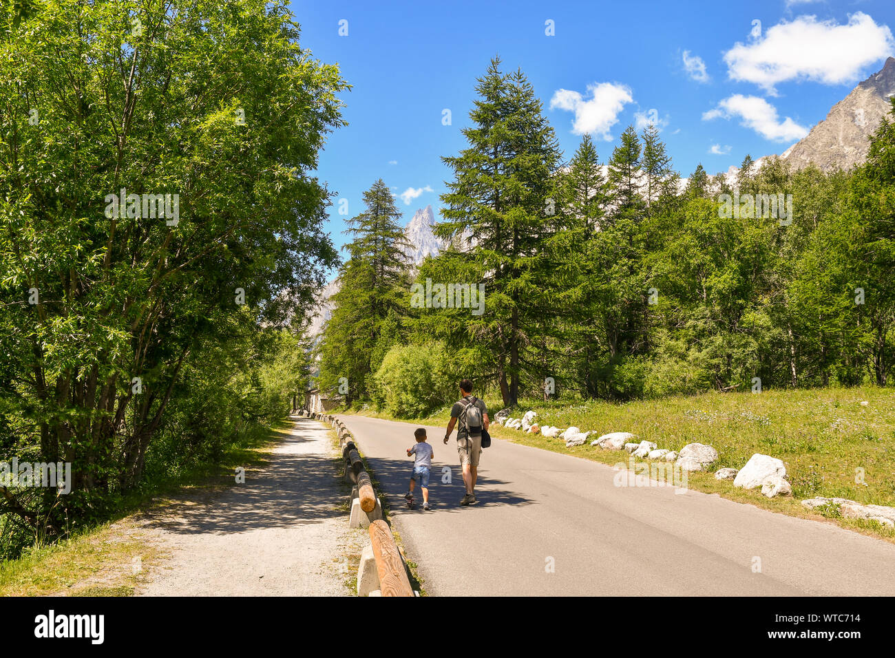 Vista panoramica della Val Ferret, una valle di Mont Blanc, con un padre e un ragazzino su uno scooter in una soleggiata giornata estiva, Courmayeur, in Valle d'Aosta, Italia Foto Stock