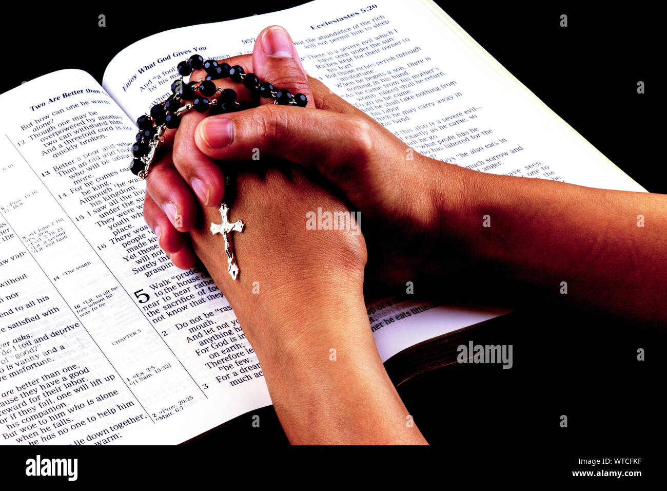 Asian womans mani giunte in preghiera con il rosario sulla bibbia Foto Stock