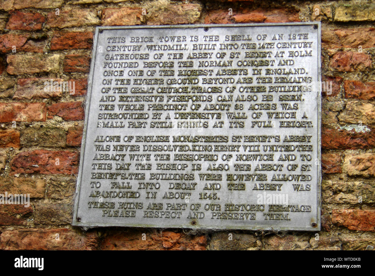 Spiegazione di placca St Benet (benedetto) a Holm Abbey con 18c il mulino a vento di resti della torre, Norfolk. L'abbazia non è mai stato sciolto dal Re Enrico VIII, a differenza di tutti gli altri Foto Stock