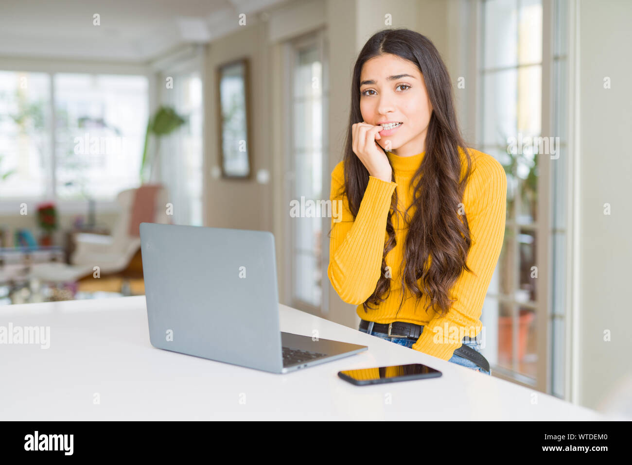 Giovane donna utilizzando computer portatile cercando stressato e nervoso con le mani sulla bocca di mordere le unghie. Problema d'ansia. Foto Stock