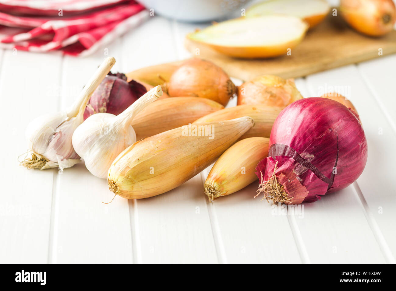 Il golden scalogno cipolla e aglio. Le lampadine di fresco sul tavolo bianco. Foto Stock