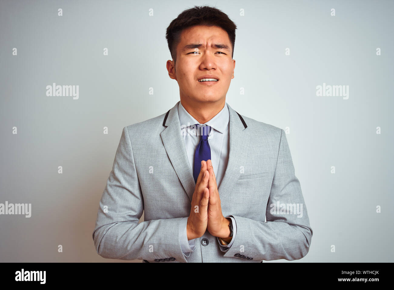 Asian businessman cinesi grigio indossare giacca e cravatta in piedi  isolato su sfondo bianco a mendicare e a pregare con le mani insieme con  speranza expres Foto stock - Alamy