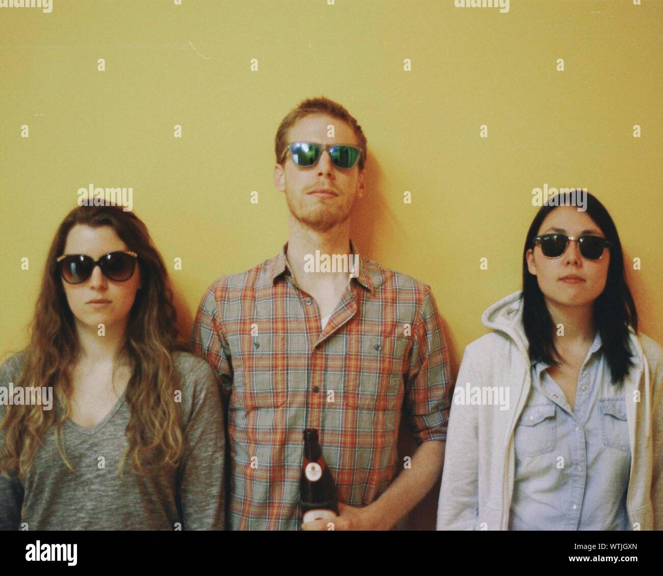 Ritratto di tre giovani adulti su sfondo giallo Foto Stock