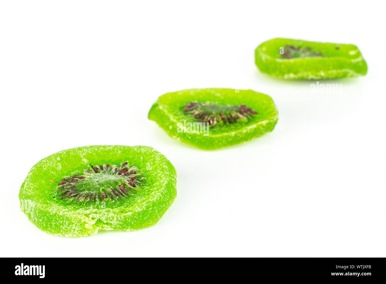 Gruppo di tre fette di dolci verdi canditi di kiwi disposta diagonalmente isolati su sfondo bianco Foto Stock