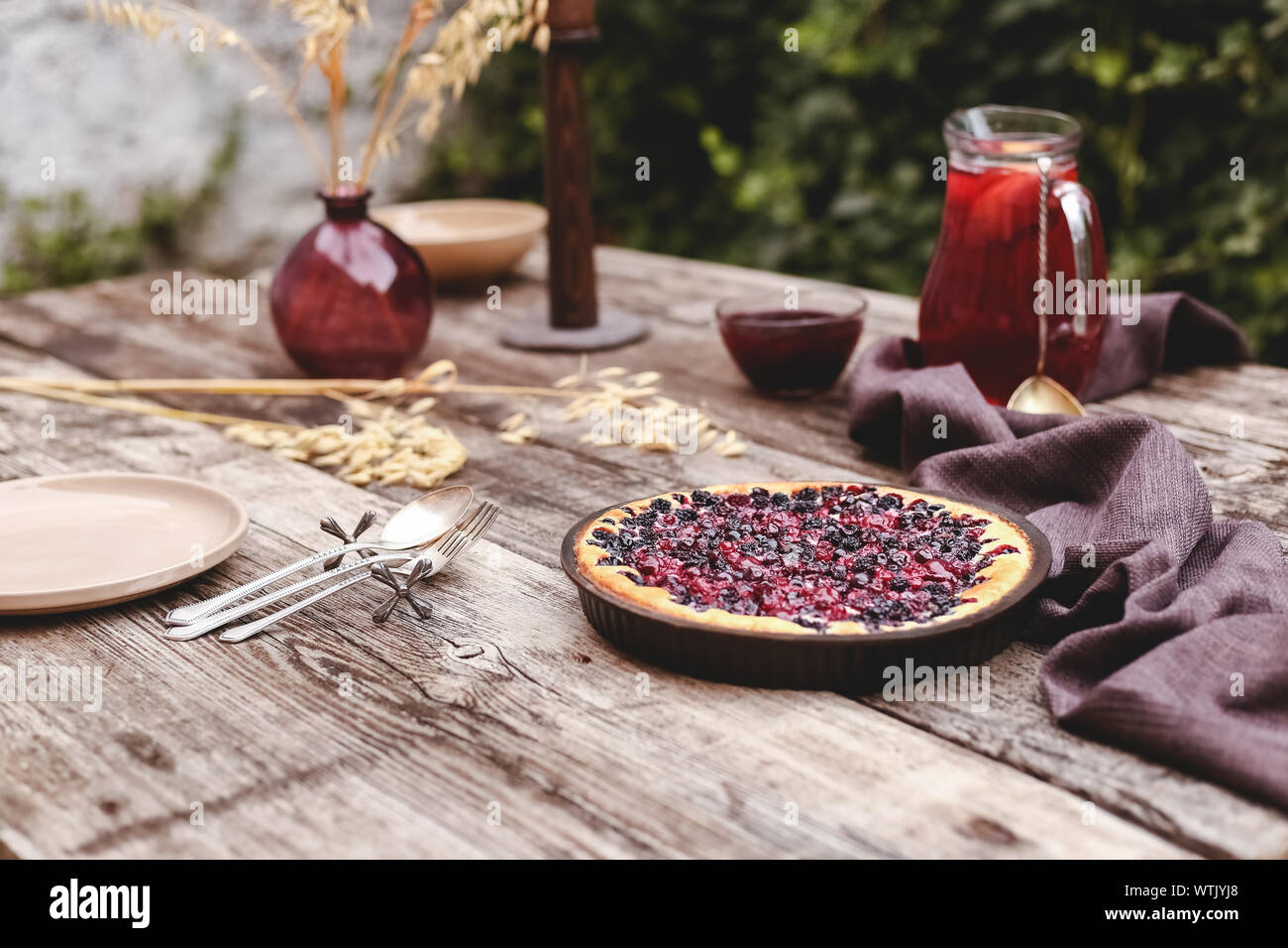 Torta di bacche con ciliegia, ribes, mora, mirtillo sul tavolo in legno in stile rustico . In casa la cheesecake. Foto Stock