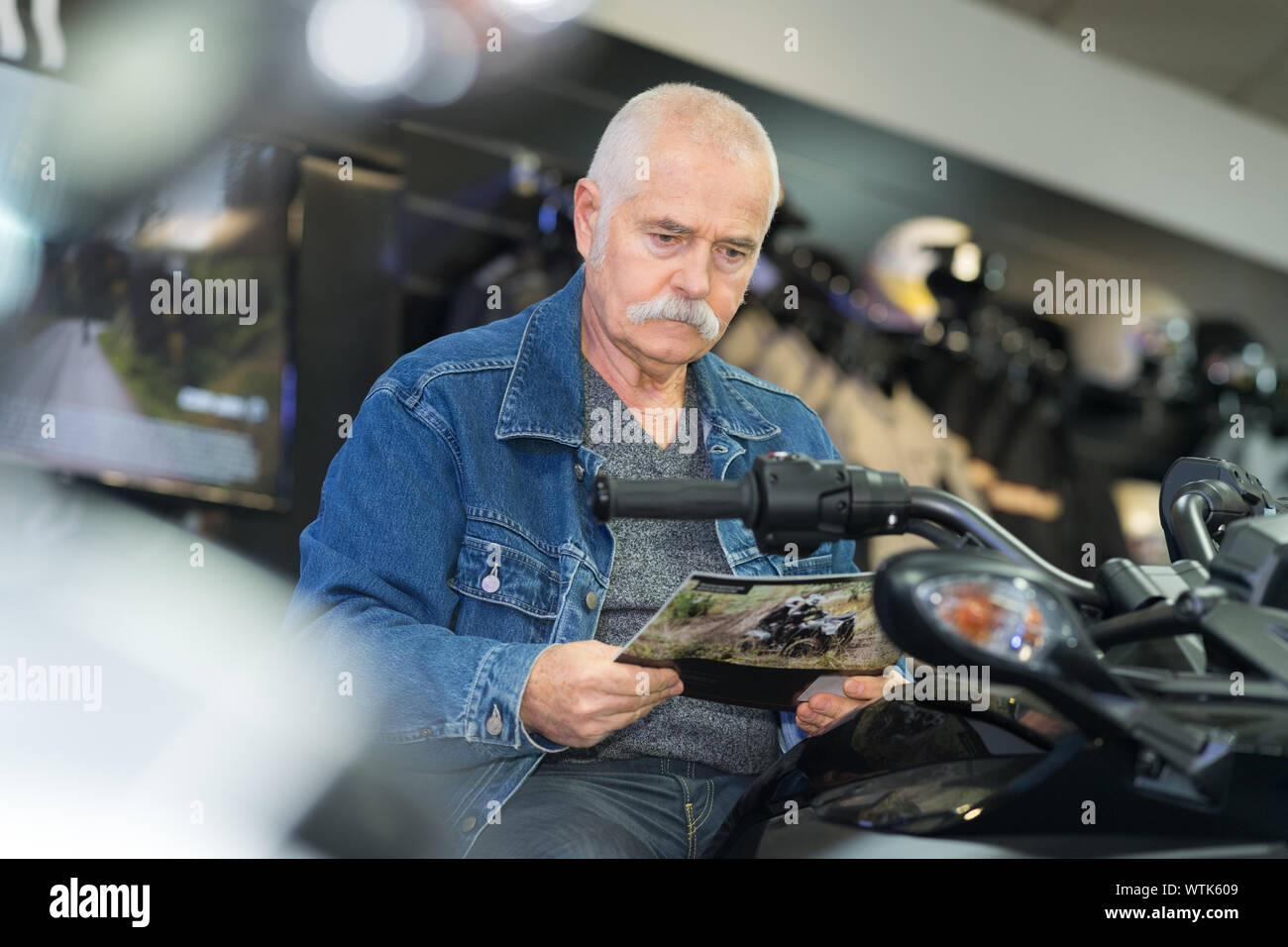 Uomo seduto sulla moto e guardando la brochure Foto Stock